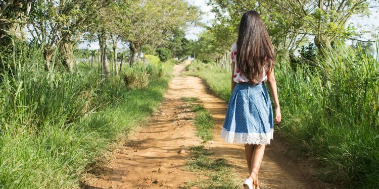 Woman Wearing Blue and White Skirt Walking Near Green Grass during Daytime