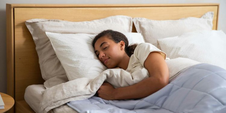 A woman sleeping in a bed with a blanket
