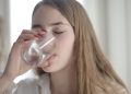 Woman in White Shirt Drinking Water From Clear Glass with Her Eyes Closed