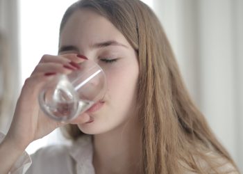 Woman in White Shirt Drinking Water From Clear Glass with Her Eyes Closed