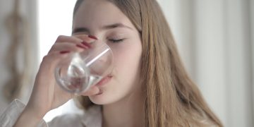 Woman in White Shirt Drinking Water From Clear Glass with Her Eyes Closed