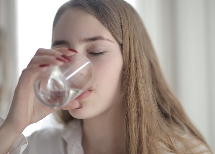 Woman in White Shirt Drinking Water From Clear Glass with Her Eyes Closed