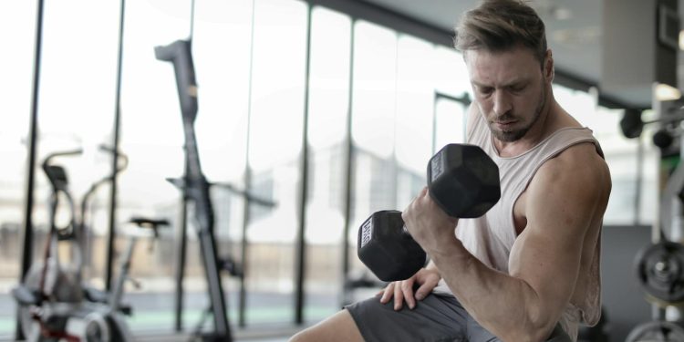 Man in White Tank Top and Grey Shorts Lifting Dumbbell