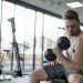 Man in White Tank Top and Grey Shorts Lifting Dumbbell