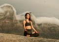 Woman in Black Sports Bra and Black Pants Sitting on Rock