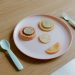 From above of plastic plate with sliced grapefruit orange lemon and lime making face near spoon and fork